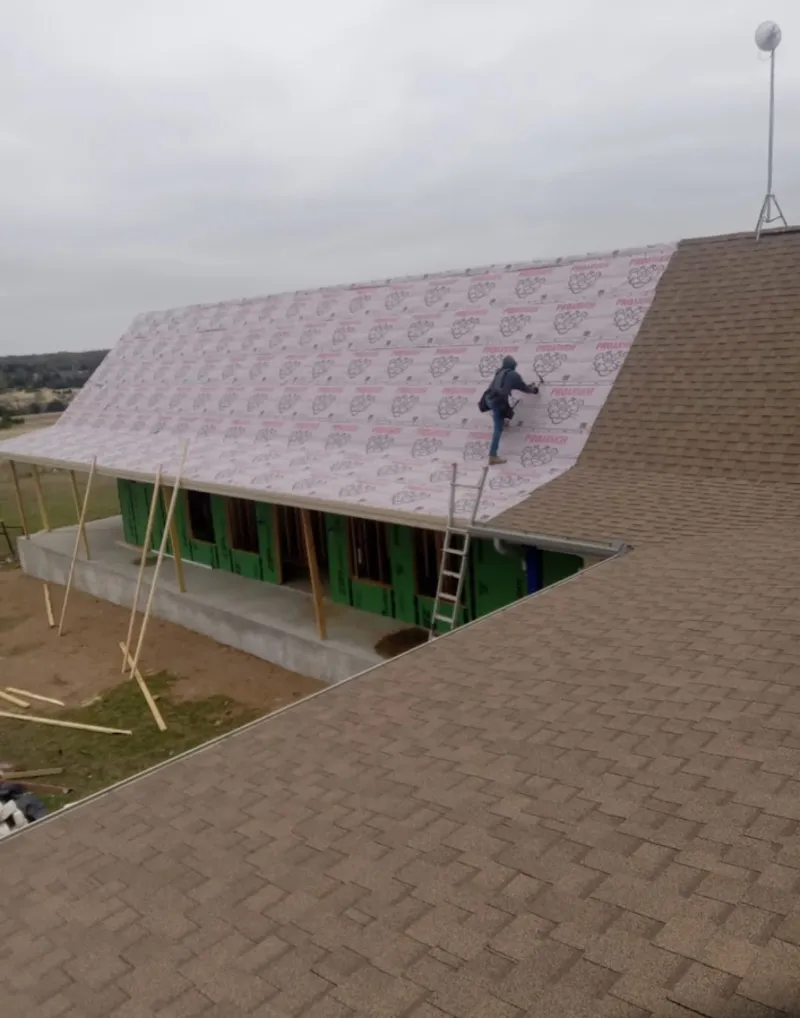 Worker preparing underlayment for a metal roof installation in Indian Trail